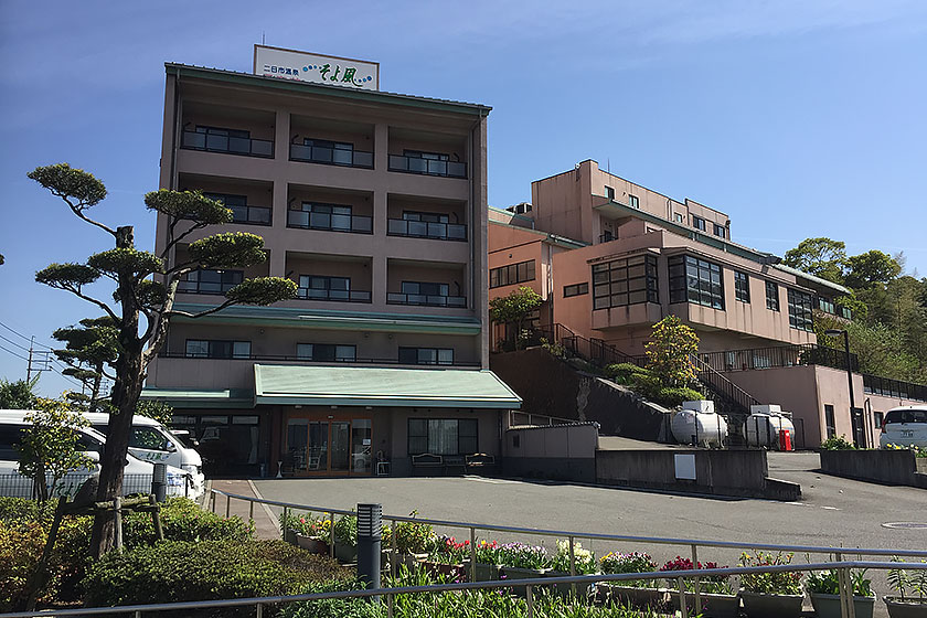 複数棟からなる介護施設の建物外観。緑色の庇を持つ1階と3階建ての本館、右奥に別棟。
